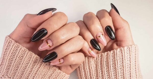 close up of black and pink nails with subtle gold design, brown sleeves showing along wrists